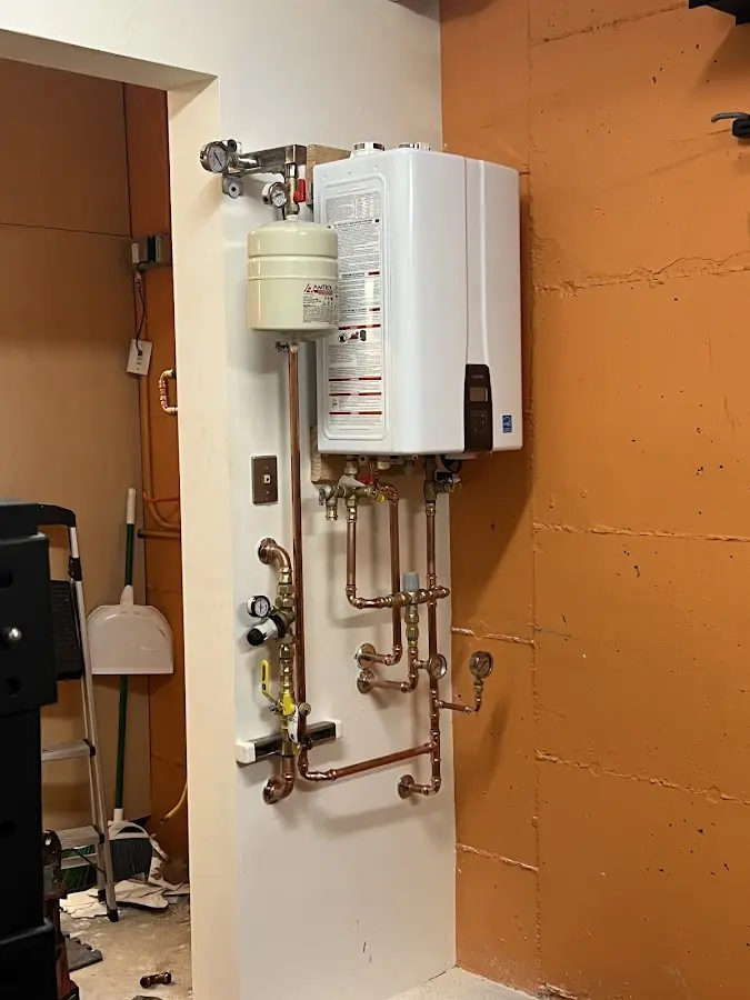 Plumbing technician inspecting water heater connections in Grand Rapids